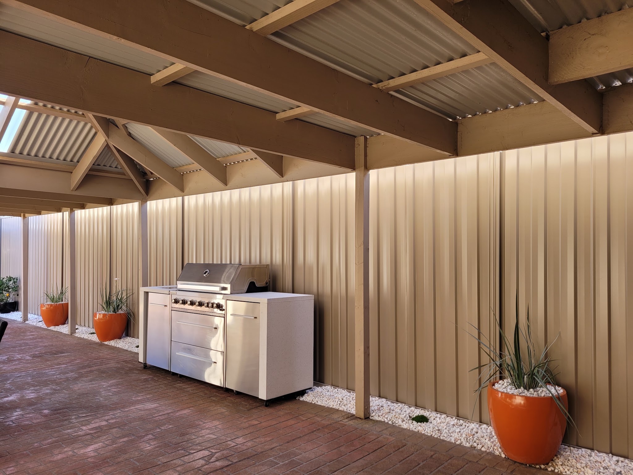 Tall Colorbond fence panels lining a covered alfresco area with an outdoor kitchen